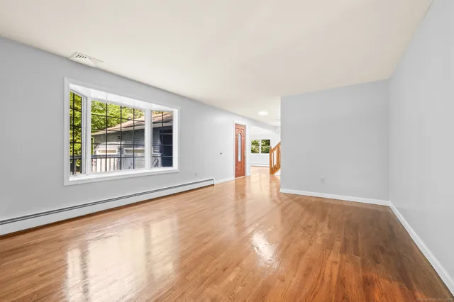 a view of an empty room with wooden floor and a window