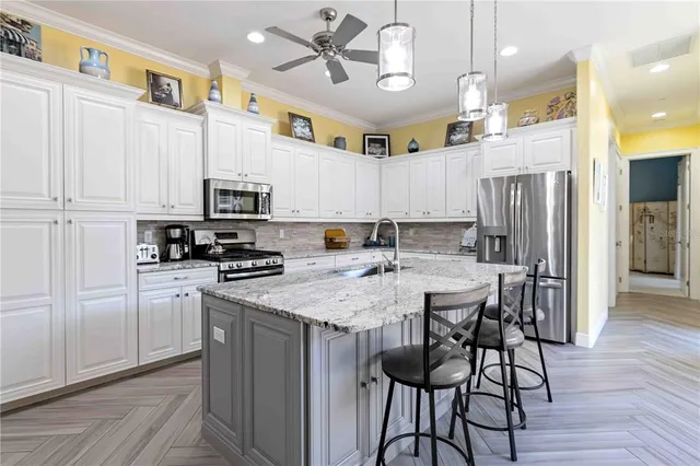 a kitchen with granite countertop stainless steel appliances a dining table and chairs
