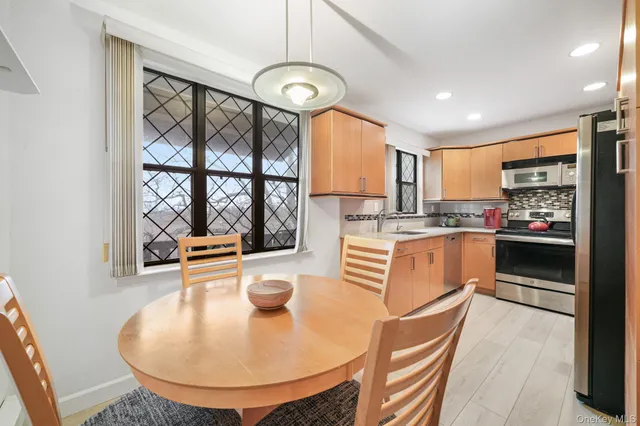 a kitchen with stainless steel appliances granite countertop a stove a sink a refrigerator cabinets and dining table