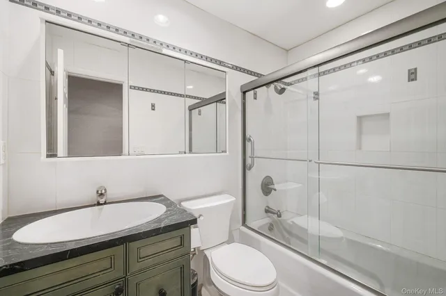a bathroom with a granite countertop sink toilet mirror and shower