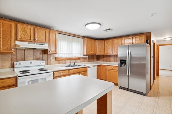189 Brook Street Clinton, MA 01510 - Photo 8 of 29 a kitchen with stainless steel appliances granite countertop a refrigerator a sink dishwasher a stove and white countertops with wooden floor