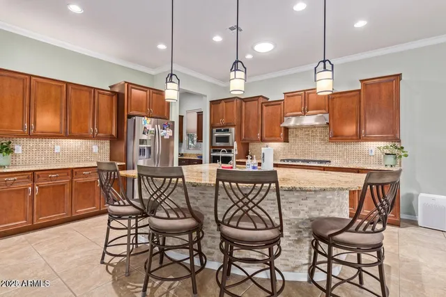 a kitchen with stainless steel appliances granite countertop a stove a sink a refrigerator a dining table and chairs with wooden floor