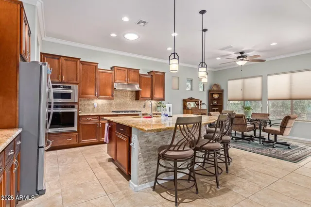 a open kitchen with stainless steel appliances granite countertop a stove top oven a sink a dining table and chairs with wooden floor