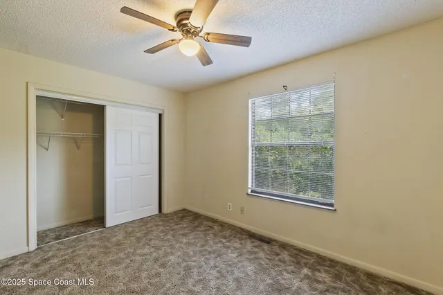 a view of empty room with window and ceiling fan
