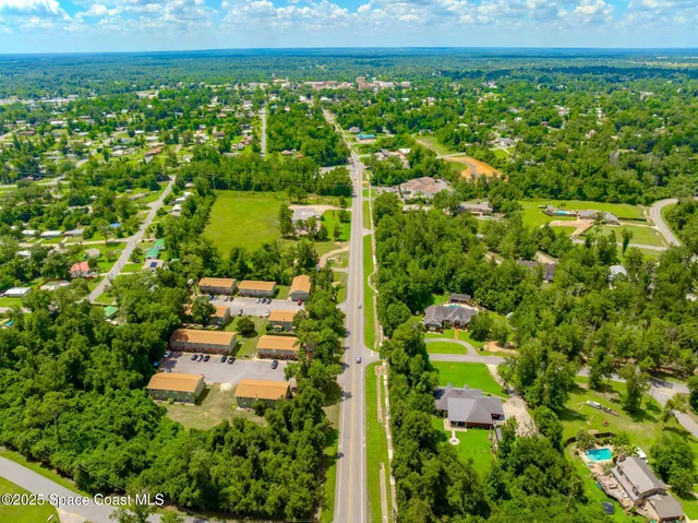 an aerial view of residential house with outdoor space and trees all around
