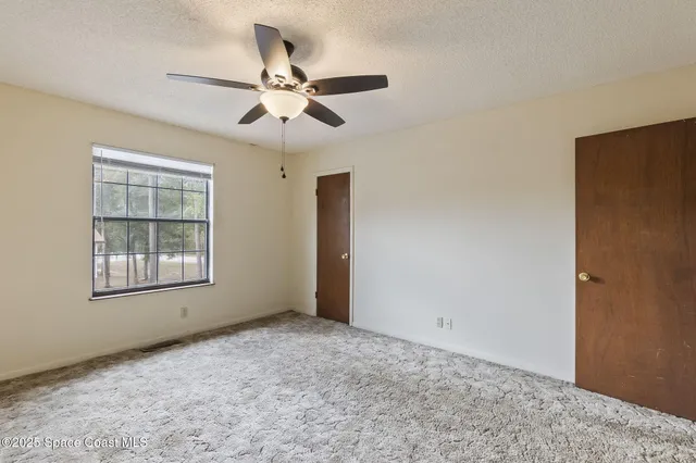 a view of an empty room with chandelier fan and fire place