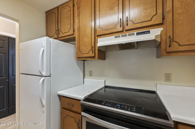 a close view of stove top oven with refrigerator and cabinets
