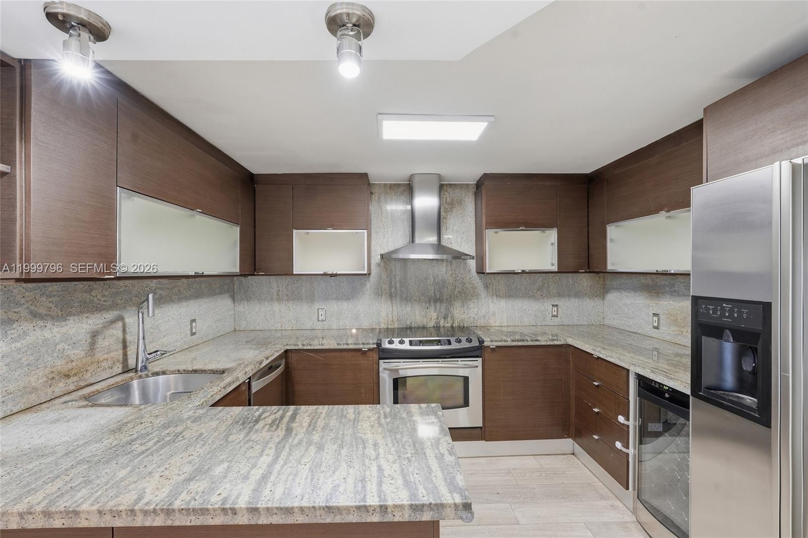 1627 Brickell Avenue, Unit 603 Miami, FL 33129 - Photo 4 of 29 a kitchen with stainless steel appliances granite countertop a sink wooden cabinets and a granite counter tops
