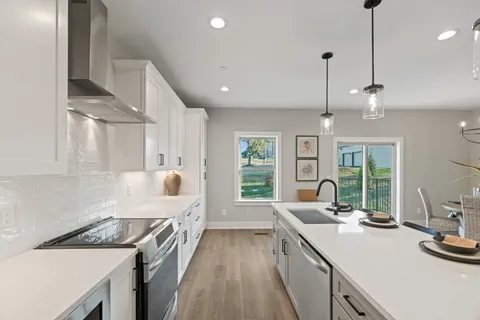 a kitchen with kitchen island granite countertop a sink a counter space appliances and cabinets