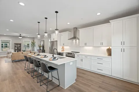 a large kitchen with stainless steel appliances granite countertop a sink a stove a refrigerator and a wooden floor