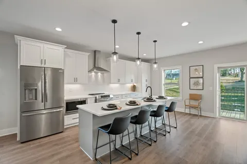 a kitchen with stainless steel appliances a dining table chairs stove refrigerator and wooden floor