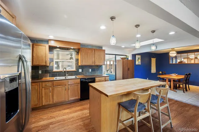 a kitchen with stainless steel appliances granite countertop a table chairs sink refrigerator and cabinets