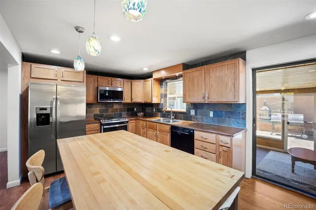 a kitchen with granite countertop a refrigerator oven a sink dishwasher a dining table and chairs with wooden floor