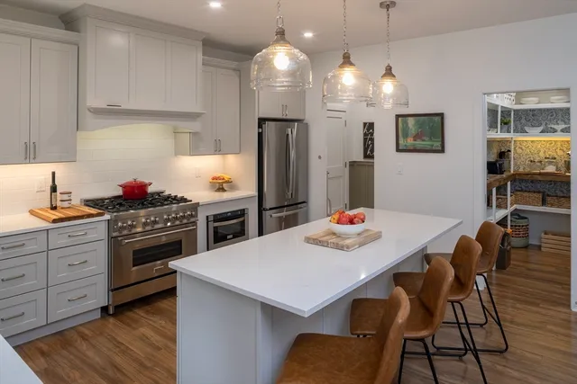 a kitchen with a dining table cabinets appliances and wooden floor
