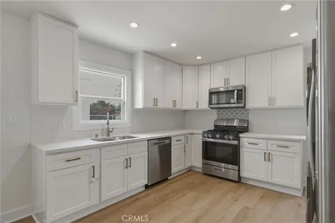 a kitchen with a sink white cabinets and stainless steel appliances