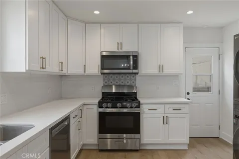 a kitchen with granite countertop white cabinets and stainless steel appliances