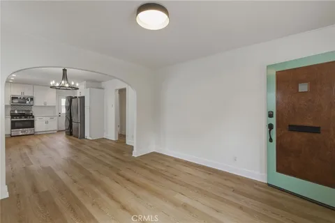 an empty room with wooden floor and chandelier
