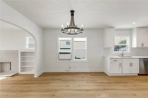 a view of an empty room with a window and kitchen area