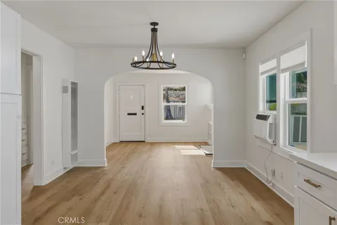 a view of an empty room with window and wooden floor