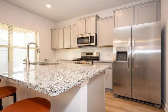 a kitchen with stainless steel appliances granite countertop a refrigerator a stove a sink a counter space and cabinets