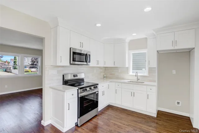 a kitchen with granite countertop a sink a stove and wooden floor