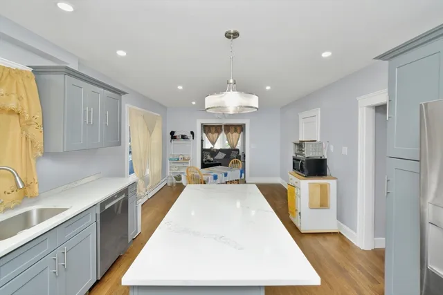 a large kitchen with kitchen island a large counter top space a sink stainless steel appliances and cabinets