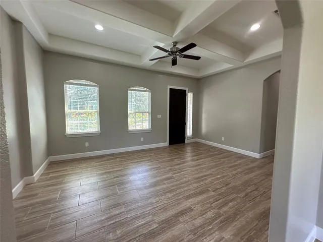 a view of an empty room with window and wooden floor