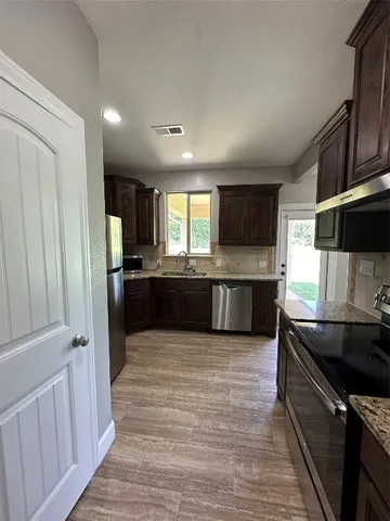 a large kitchen with stainless steel appliances granite countertop a stove a sink and a refrigerator