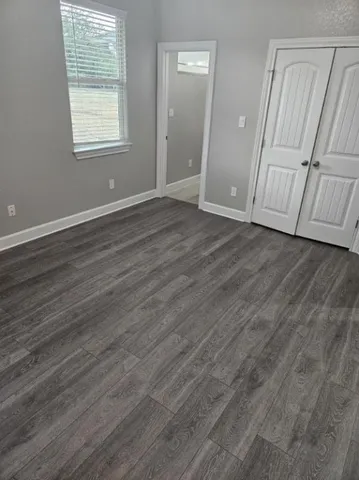 an empty room with wooden floor and window