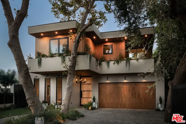a front view of a house with plants and trees