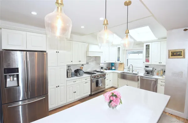 a large kitchen with kitchen island a large counter top space a sink stainless steel appliances and cabinets