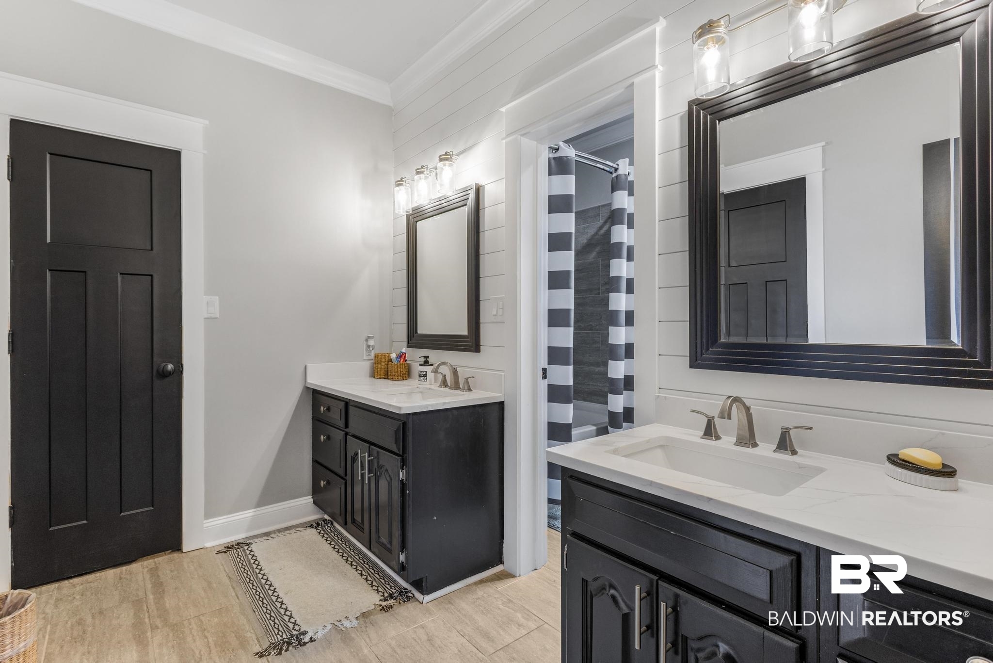 83 Caisson Trace Daphne, AL 36527 - Photo 45 of 63 Dual vanity bathroom featuring black cabinetry, light stone countertops, brushed nickel fixtures, wood-finish flooring, and white shiplap wall accents