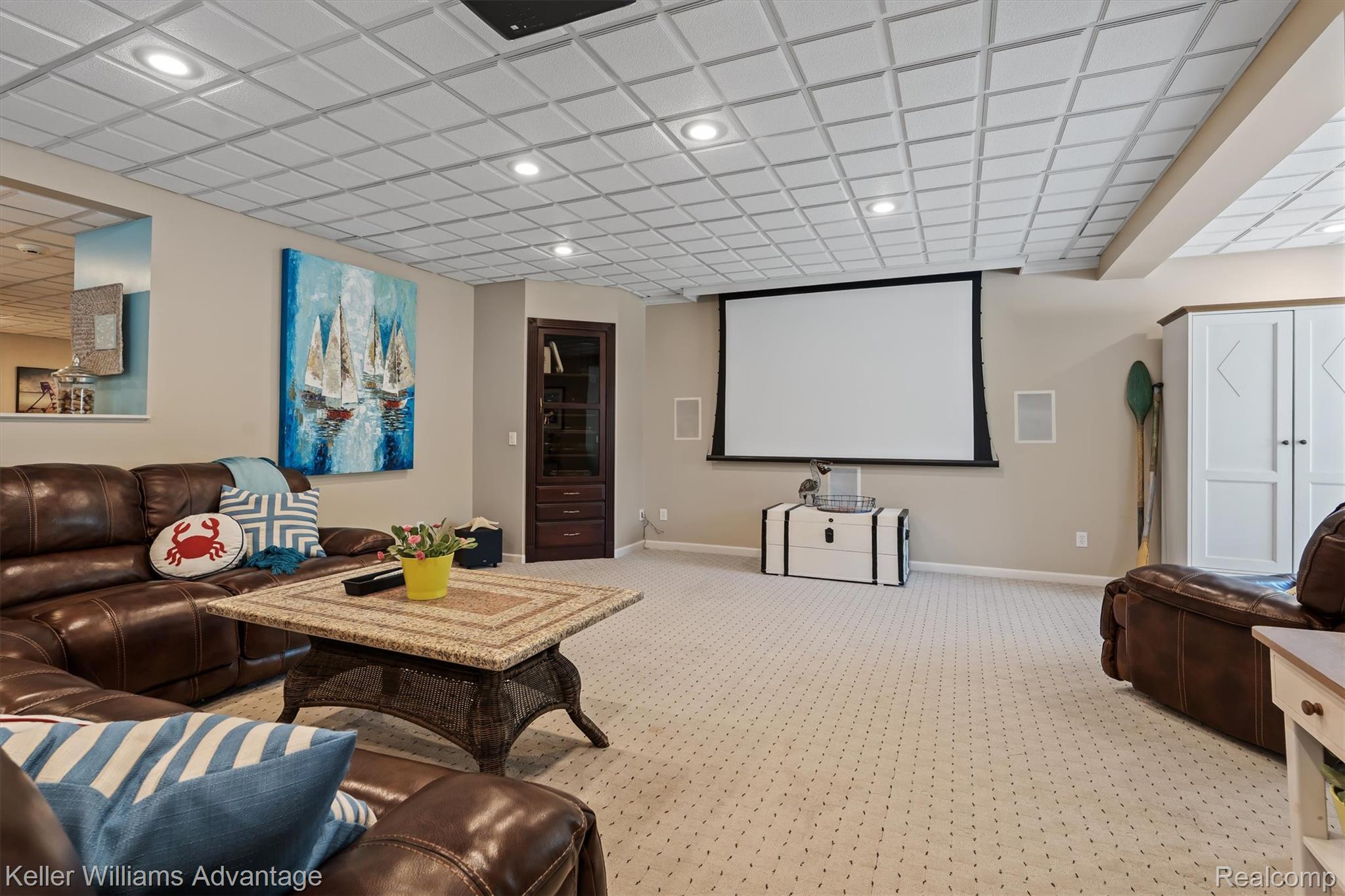 22878 Tree Top Court South Lyon, MI 48178 - Photo 29 of 75 Recessed lighting illuminates the coffered ceiling in this entertainment space, featuring a projection screen, built-in speakers, and neutral patterned carpeting