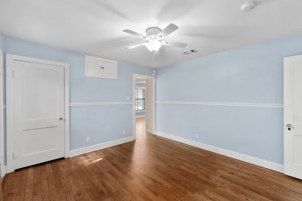 an empty room with wooden floor closet and windows