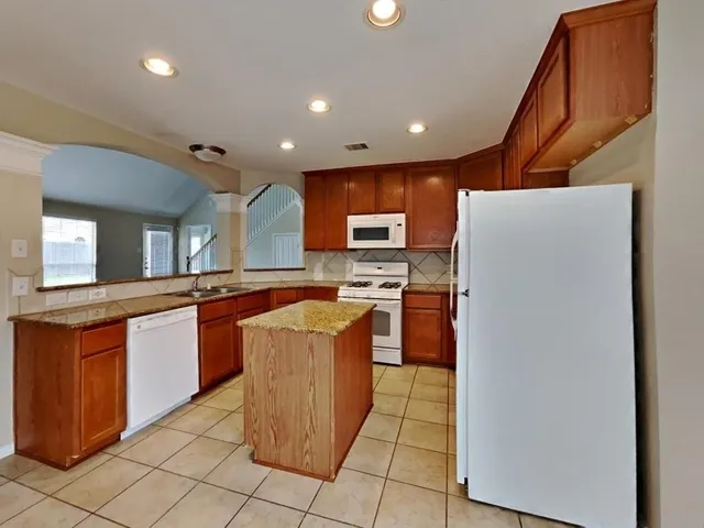 a kitchen with stainless steel appliances granite countertop a refrigerator a sink a stove top oven and a dishwasher