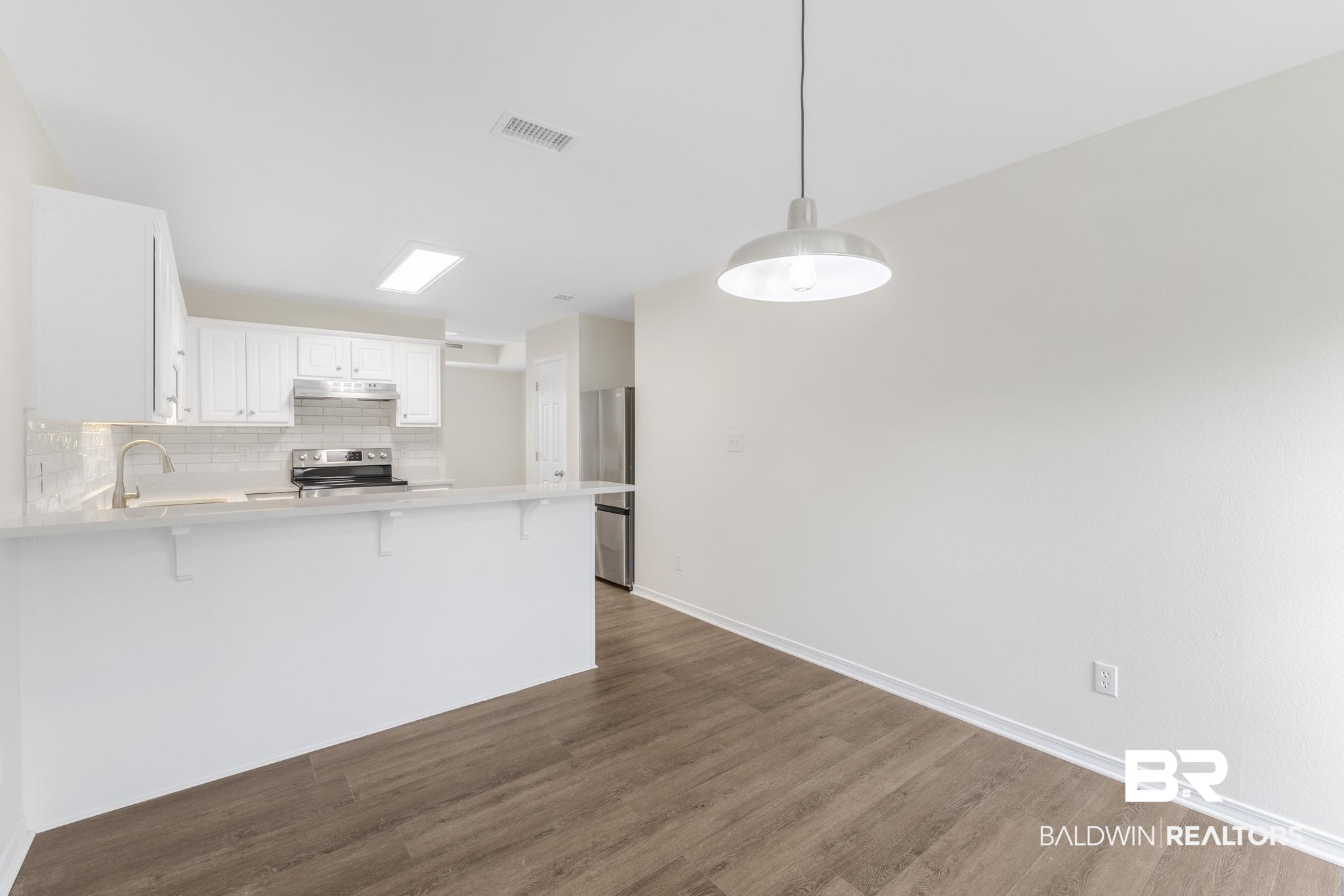 16330 Absalom Street Foley, AL 36535 - Photo 22 of 42 Kitchen with a breakfast bar, appliances with stainless steel finishes, white cabinets, decorative light fixtures, and kitchen peninsula