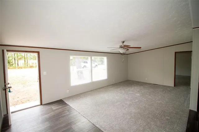 an empty room with windows and chandelier fan