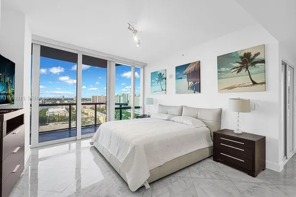 a bedroom with a large bed and a flat tv screen on dresser