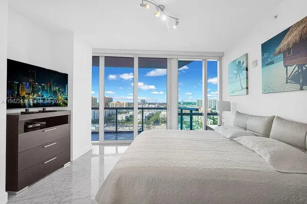 a bedroom with a large bed and a flat tv screen