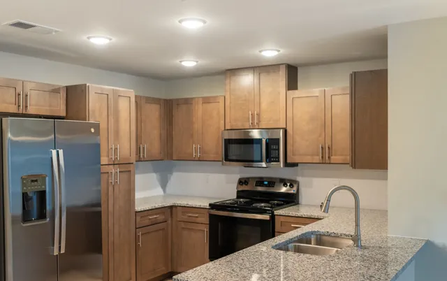 a kitchen with kitchen island granite countertop stainless steel appliances and wooden cabinets