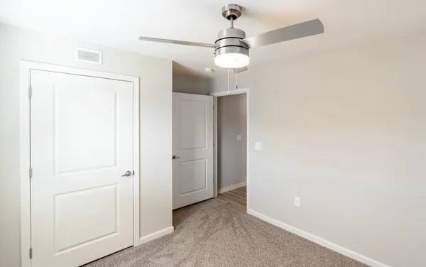 an empty room with an entryway door and fan