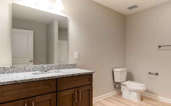 a bathroom with a granite countertop sink a toilet and a mirror