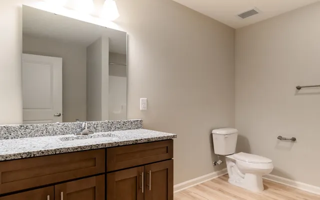 a bathroom with a granite countertop sink a toilet and a mirror