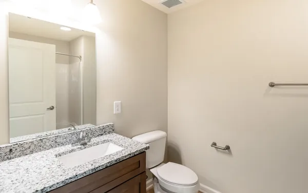 a bathroom with a granite countertop sink a toilet and a mirror