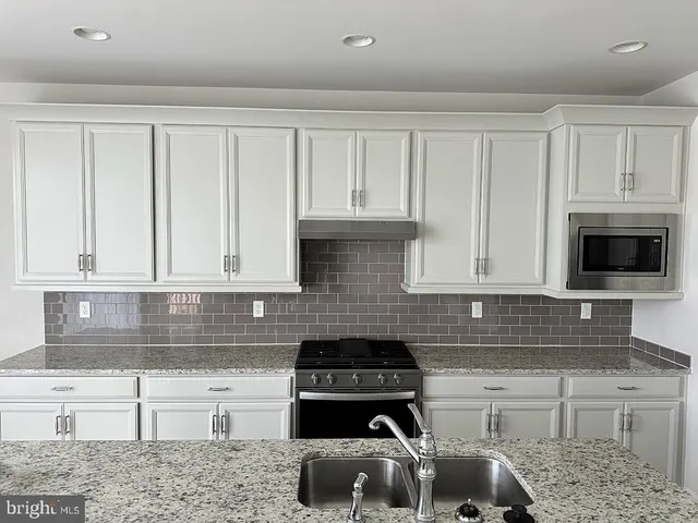 a kitchen with granite countertop white cabinets and stainless steel appliances