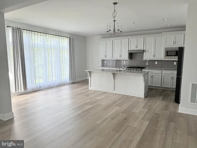 a kitchen with stainless steel appliances granite countertop a stove top oven a refrigerator a sink and dishwasher with wooden floor