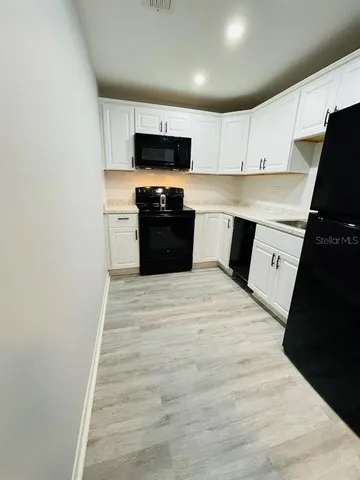 a kitchen with granite countertop white cabinets and black appliances