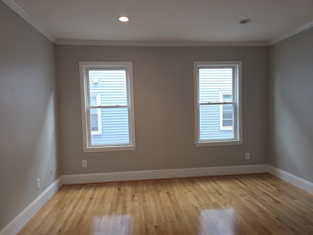 574 Washington Street, Unit 2 Boston, MA 02135 - Photo 2 of 11 an empty room with wooden floor and windows