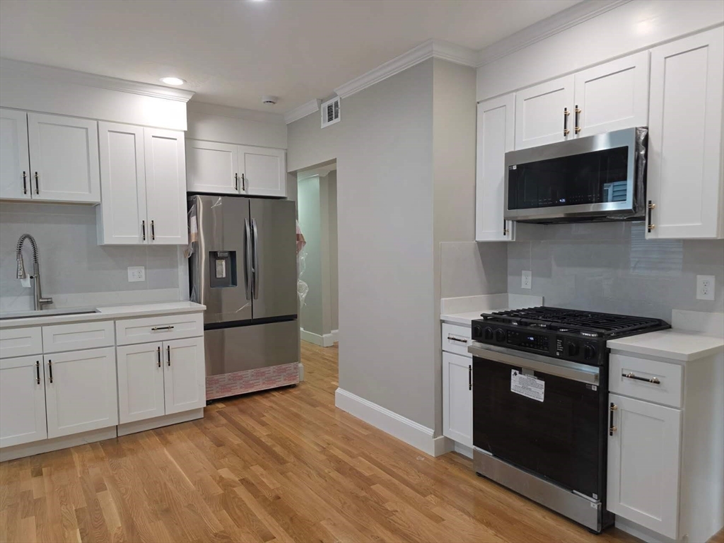 574 Washington Street, Unit 2 Boston, MA 02135 - Photo 4 of 11 a kitchen with stainless steel appliances a stove a microwave a sink and cabinets