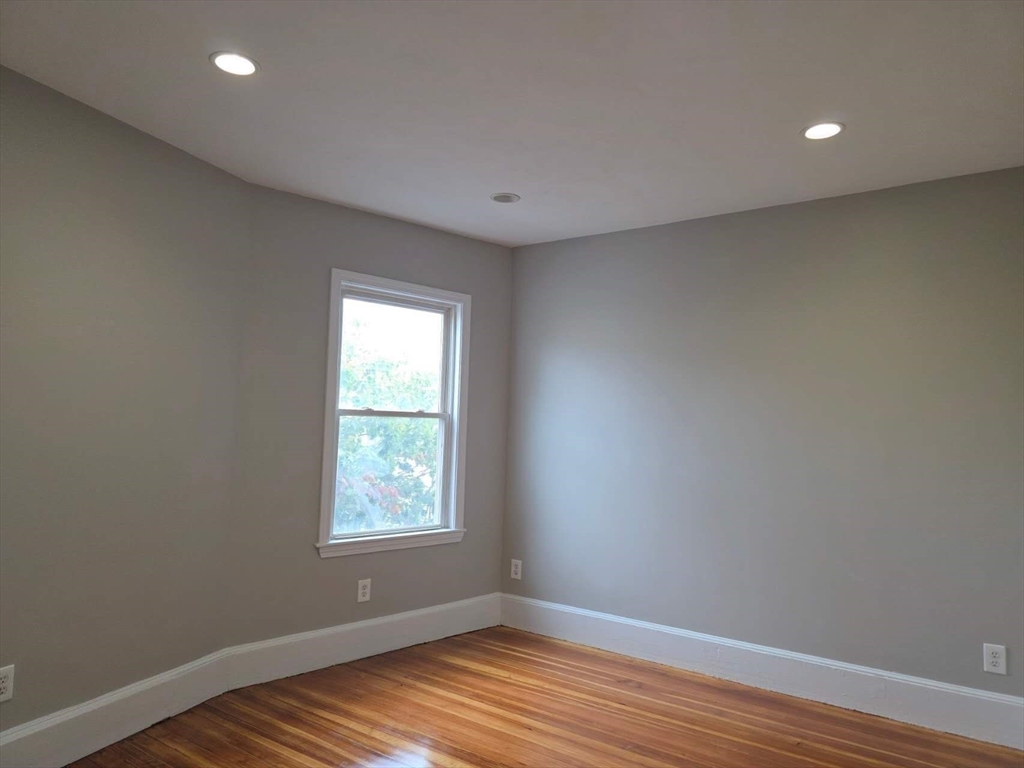 574 Washington Street, Unit 2 Boston, MA 02135 - Photo 7 of 11 a view of an empty room with wooden floor and a window
